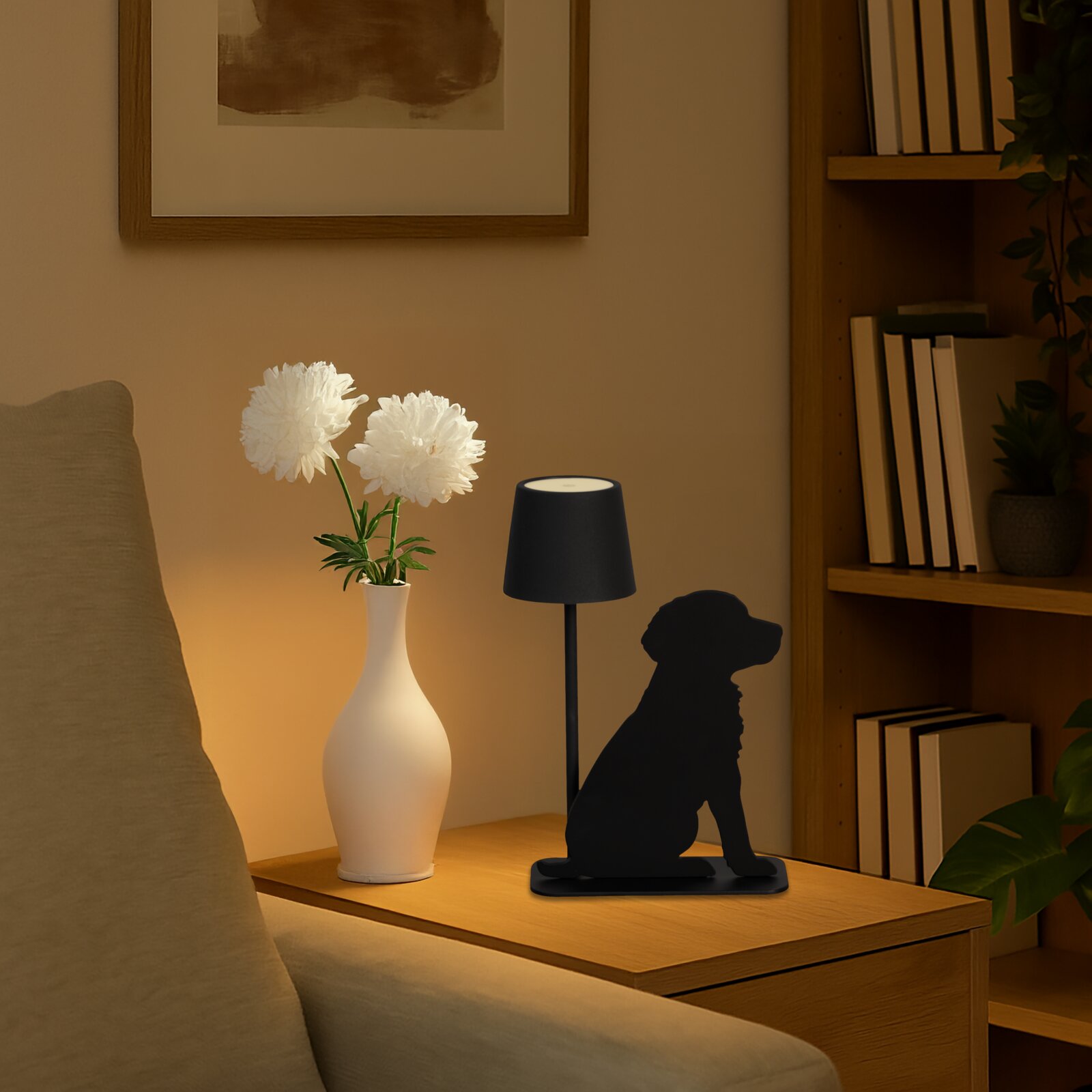 Akku-Tischleuchte in Form eines sitzenden Hundes, seitliche Perspektive, auf einem Tisch neben einer Vase mit weißen Blumen.