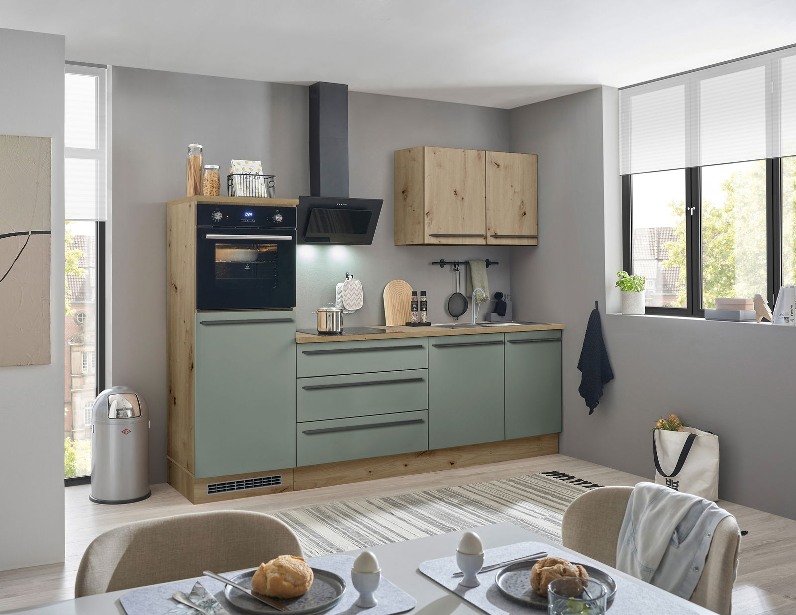 Moderne Küchenzeile in Holzoptik mit grünen Fronten, eingebautem Ofen und Dunstabzugshaube, seitliche Perspektive