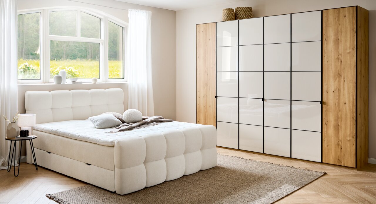 Gemütliches Boxbett in einem hellen Schlafzimmer mit großem Fenster, moderner Kleiderschrank und stilvolle Dekorationen, seitliche Perspektive.