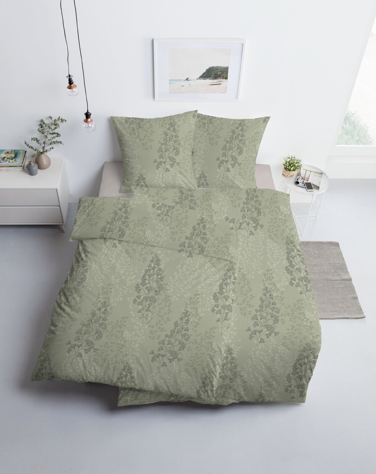 Salbeigrüne Bettwäsche mit elegantem floralem Blättermuster, aus leicht erhöhter Frontalperspektive auf einem Doppelbett im hellen Schlafzimmer gezeigt