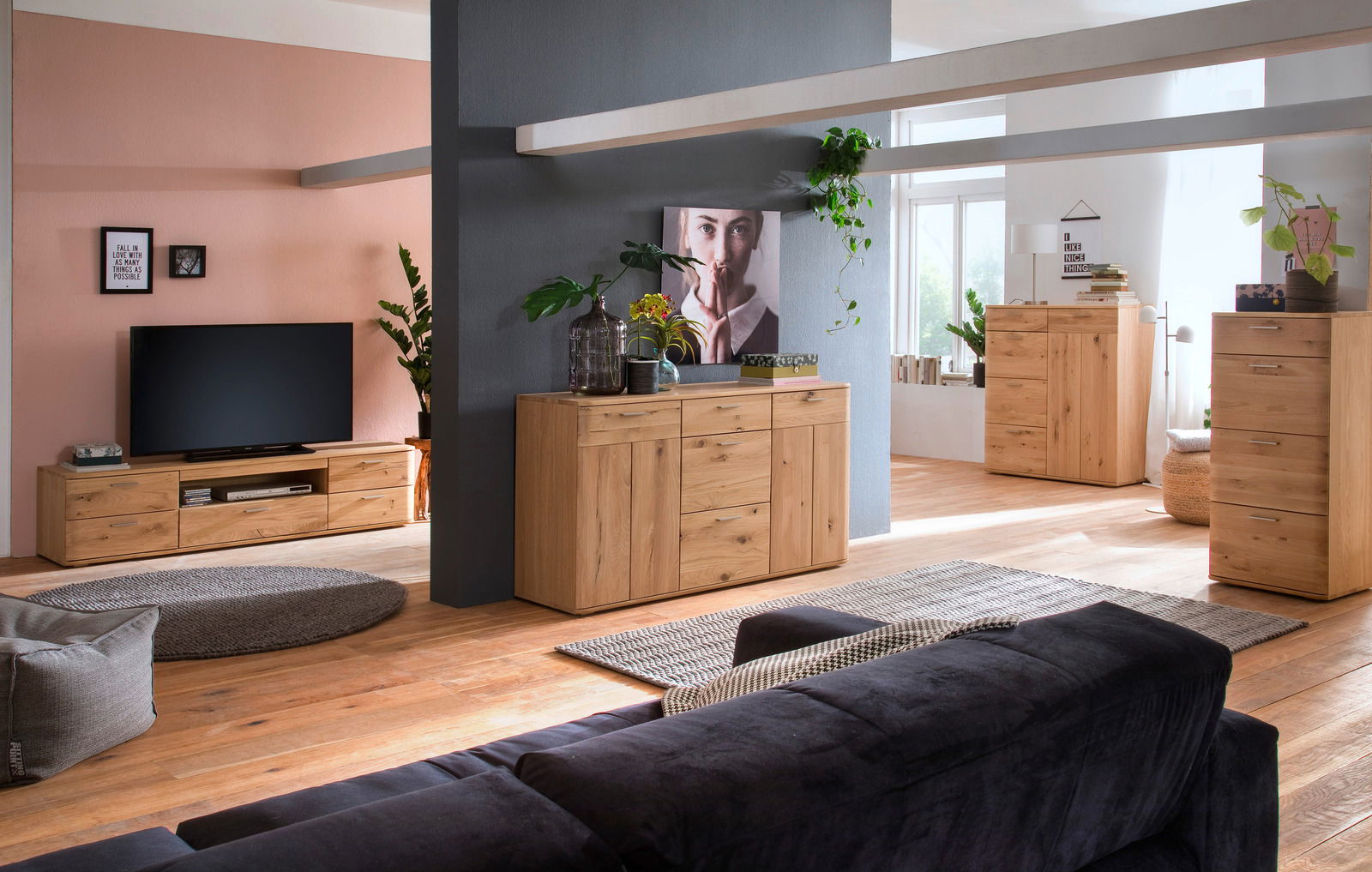 Wohnzimmer mit Holzmöbeln, darunter ein TV-Lowboard, ein Sideboard und eine Kommode, aus der Perspektive eines Sofas betrachtet.