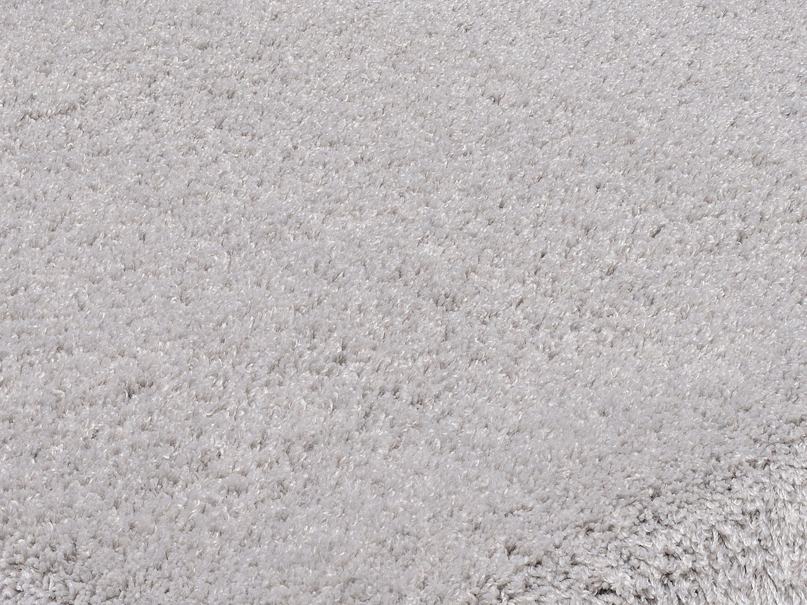 Nahaufnahme eines weichen, hellgrauen Teppichs mit flauschiger Textur.