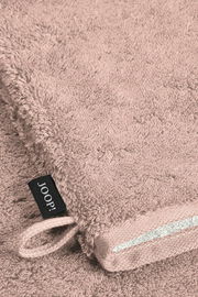 Nahaufnahme eines rosafarbenen Waschhandschuhs mit einer Schlaufe und einem schwarzen Etikett mit der Aufschrift 'JOOP!'