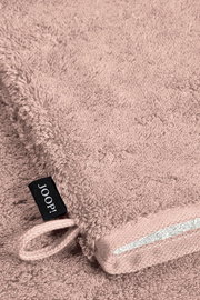 Nahaufnahme eines rosafarbenen Waschhandschuhs mit einer Schlaufe und einem schwarzen Etikett mit der Aufschrift 'JOOP!'