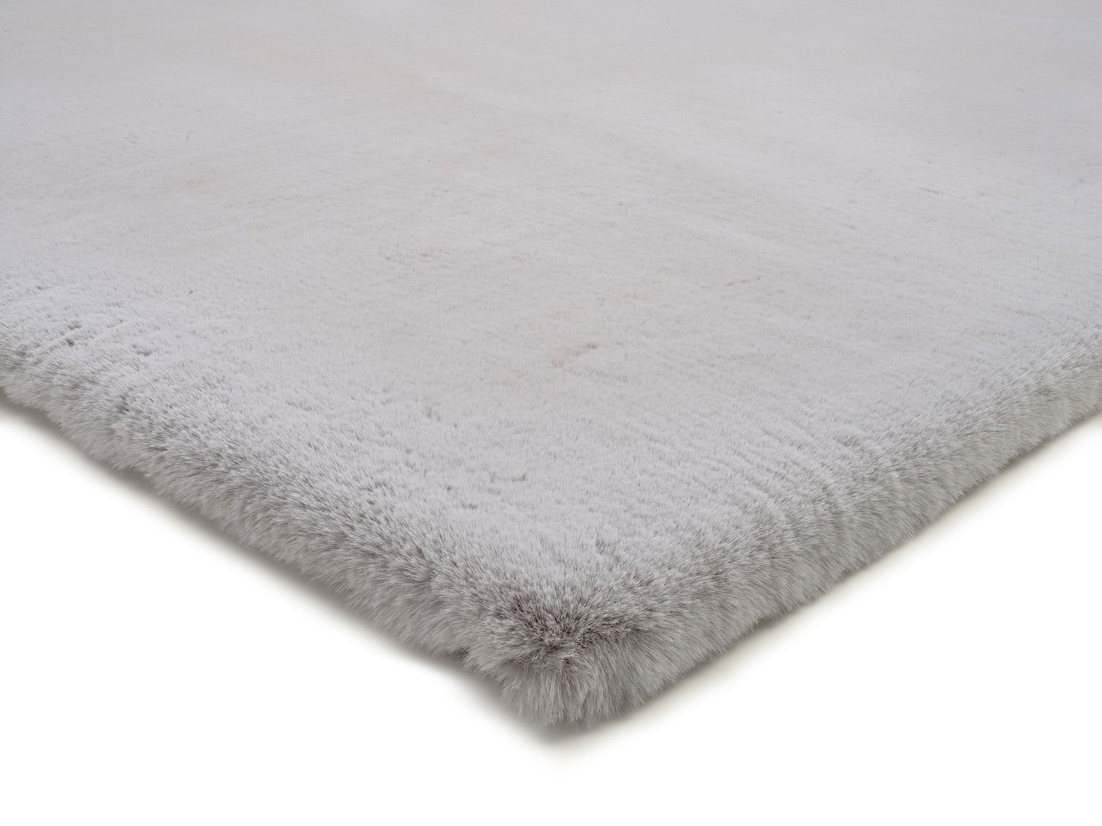 Nahaufnahme eines weichen, hellgrauen Fellteppichs aus der Seitenperspektive.