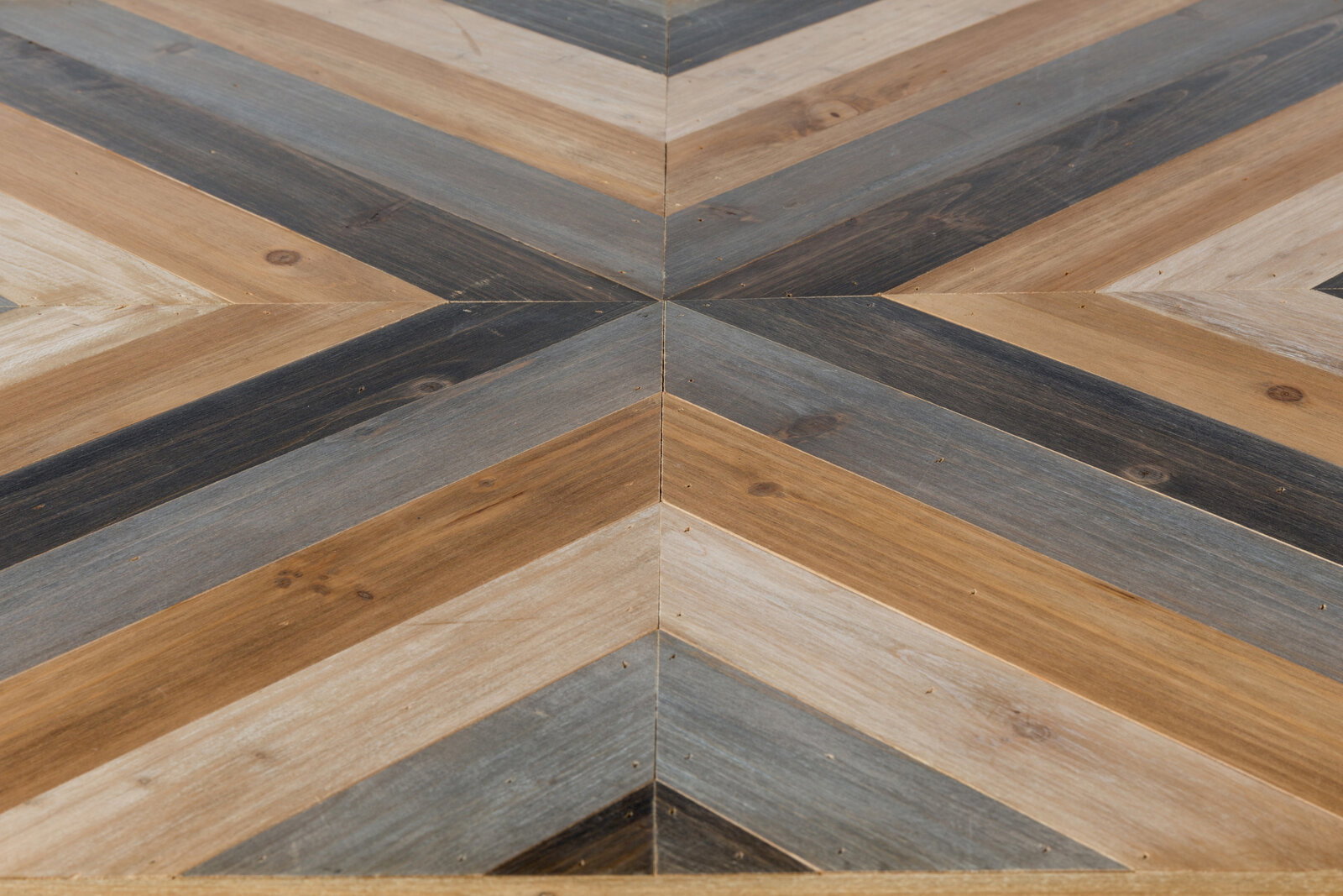 Nahaufnahme eines Couchtischs mit geometrischem Muster aus Holz in verschiedenen Brauntönen, von oben betrachtet.