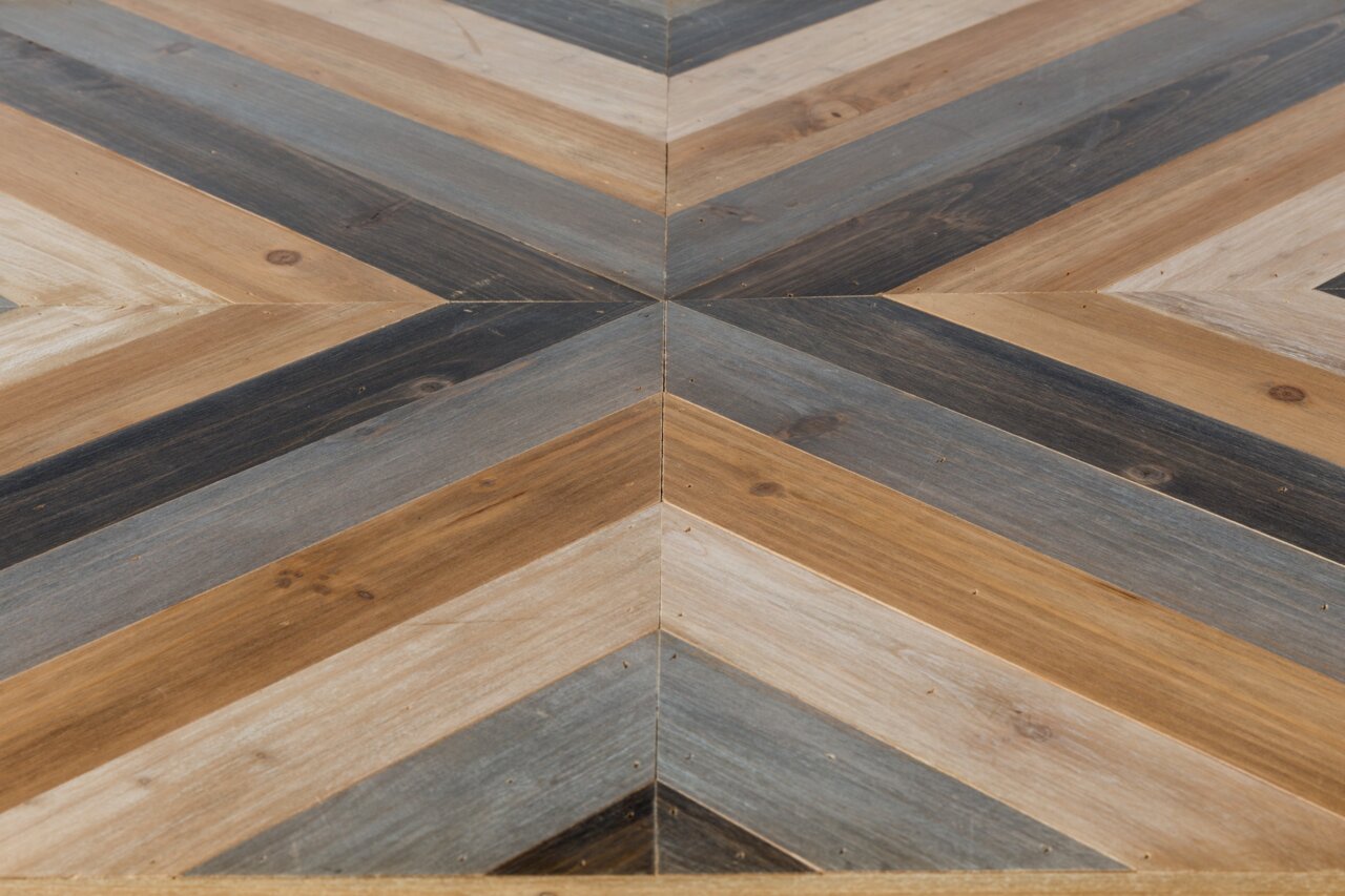 Nahaufnahme eines Couchtischs mit geometrischem Muster aus Holz in verschiedenen Brauntönen, von oben betrachtet.