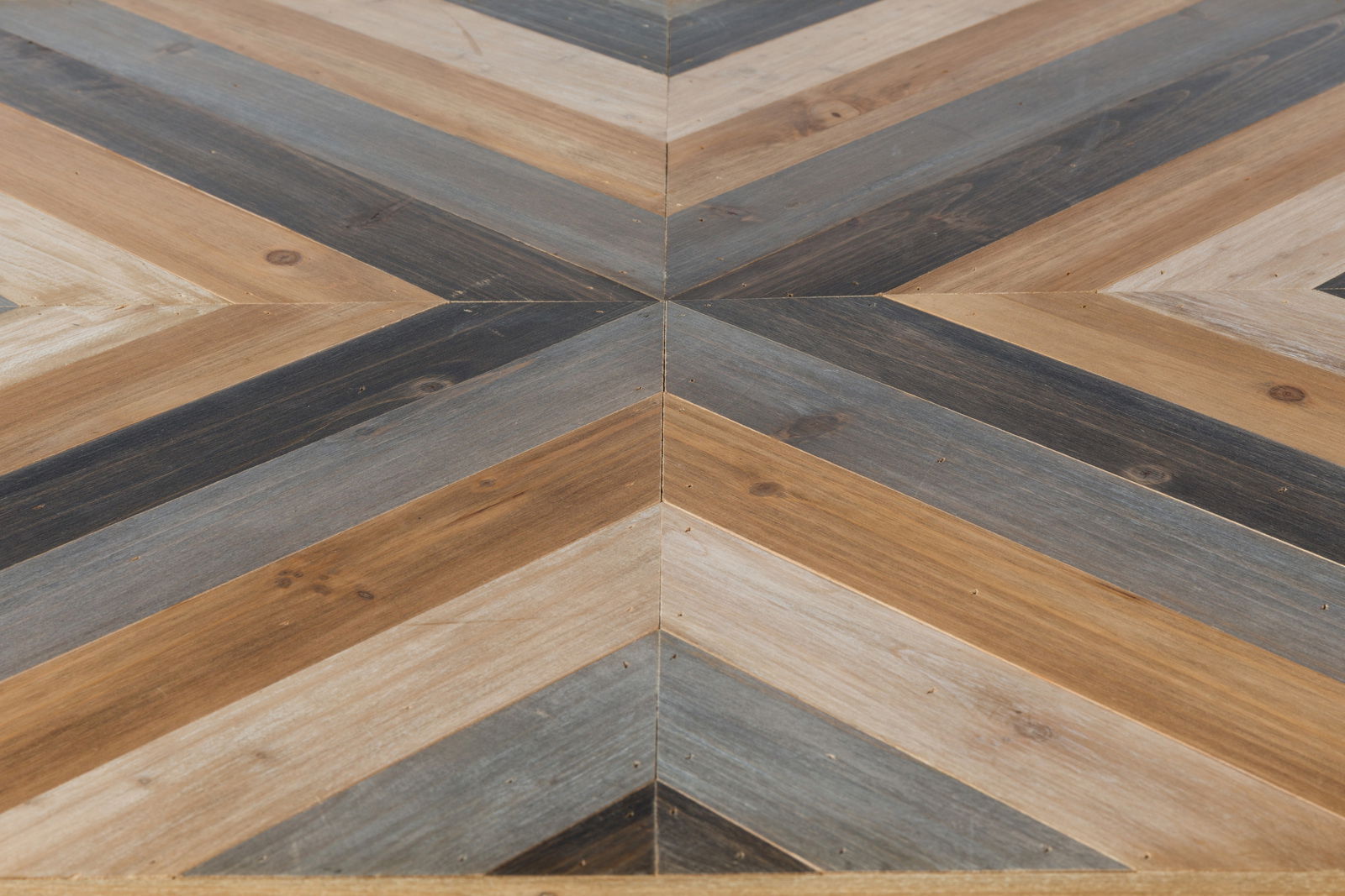 Nahaufnahme eines Couchtischs mit geometrischem Muster aus Holz in verschiedenen Brauntönen, von oben betrachtet.