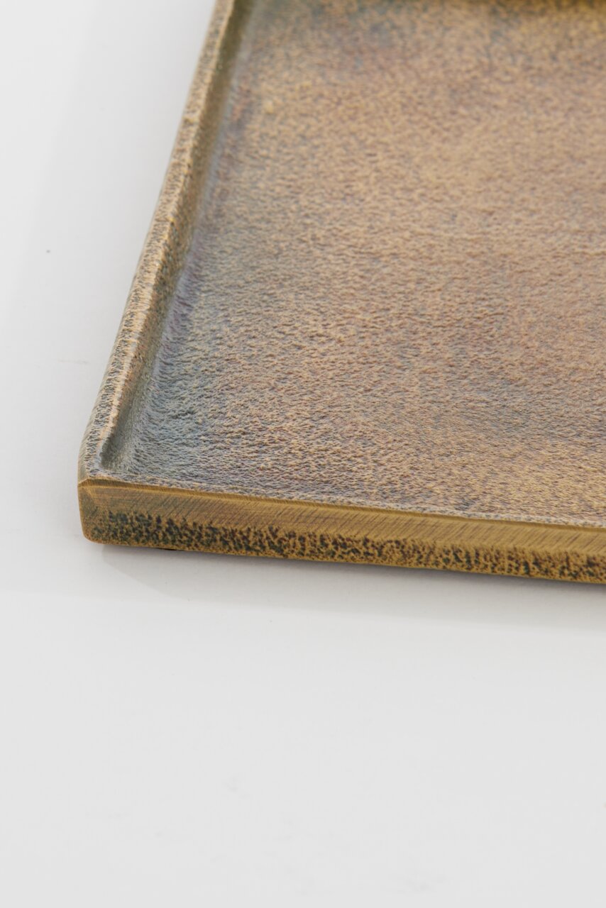 Nahaufnahme einer rechteckigen, flachen Schale mit strukturierter, bronzefarbener Oberfläche, aus der Seitenperspektive fotografiert.