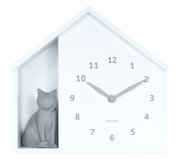 Witte wandklok in de vorm van een huisje met een grijs kattenfiguurtje aan de linkerkant, gezien van voren.