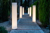 Beleuchteter Gartenweg mit mehreren zylinderförmigen Stehlampen der Serie Fity 100 von New Garden, seitliche Perspektive.