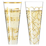 Zwei Champagnergläser mit goldenen Verzierungen, eines mit Notenlinien und das andere mit Herzmustern, gefüllt mit sprudelndem Getränk, seitliche Perspektive.