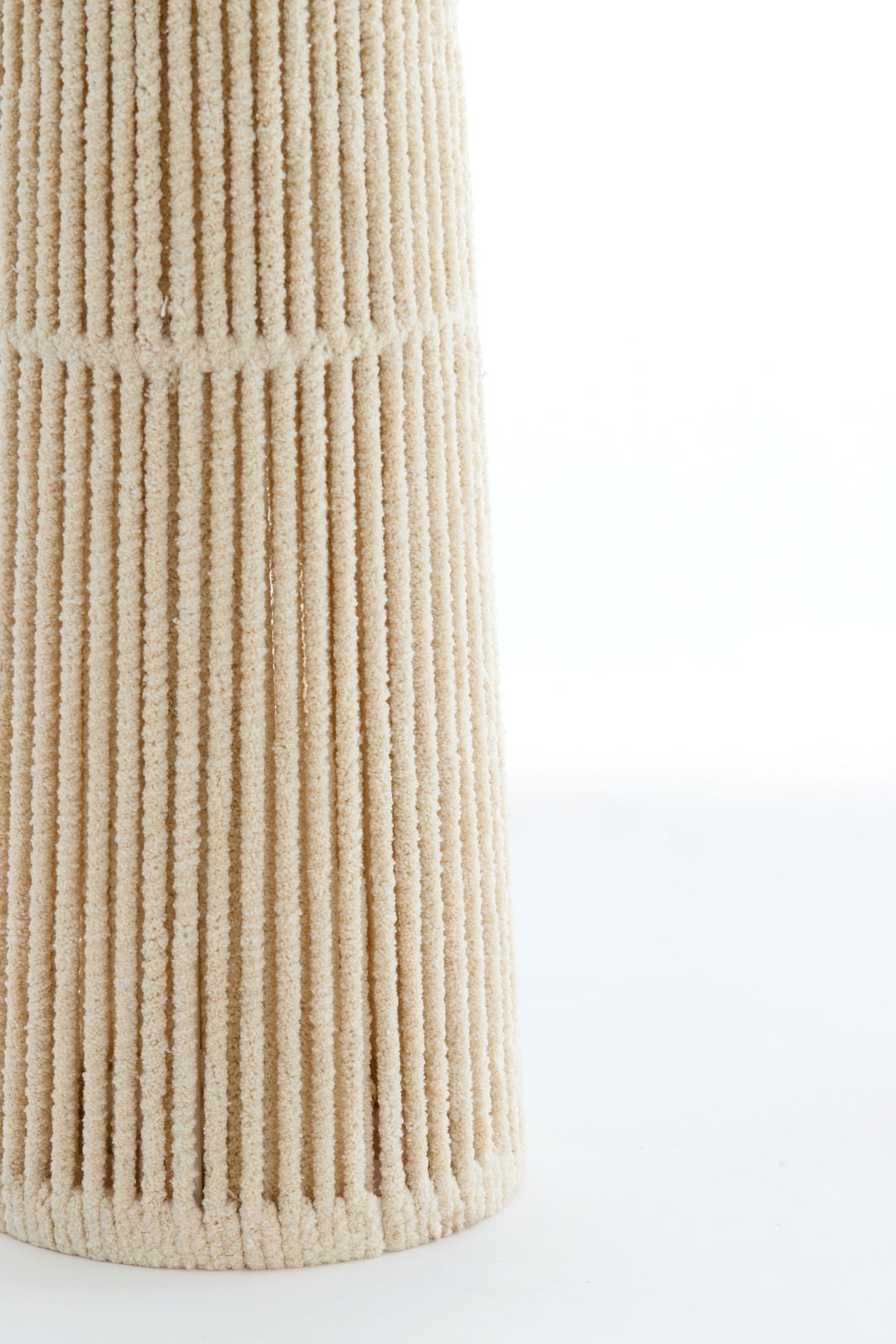 Nahaufnahme der strukturierten Oberfläche einer Stehleuchte in beige mit vertikalen Rillen.