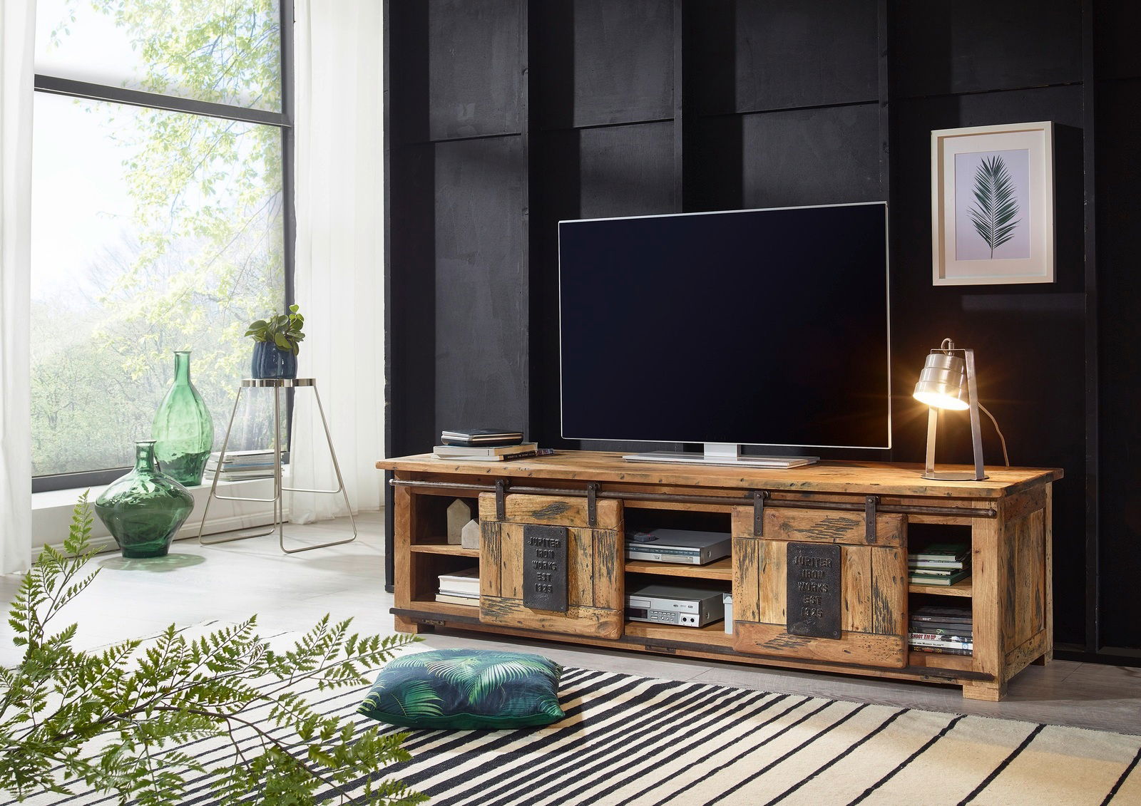 Rustikales TV-Lowboard aus Holz mit Schiebetüren, dekoriert mit einer Tischlampe und einem großen Fernseher, seitliche Perspektive.