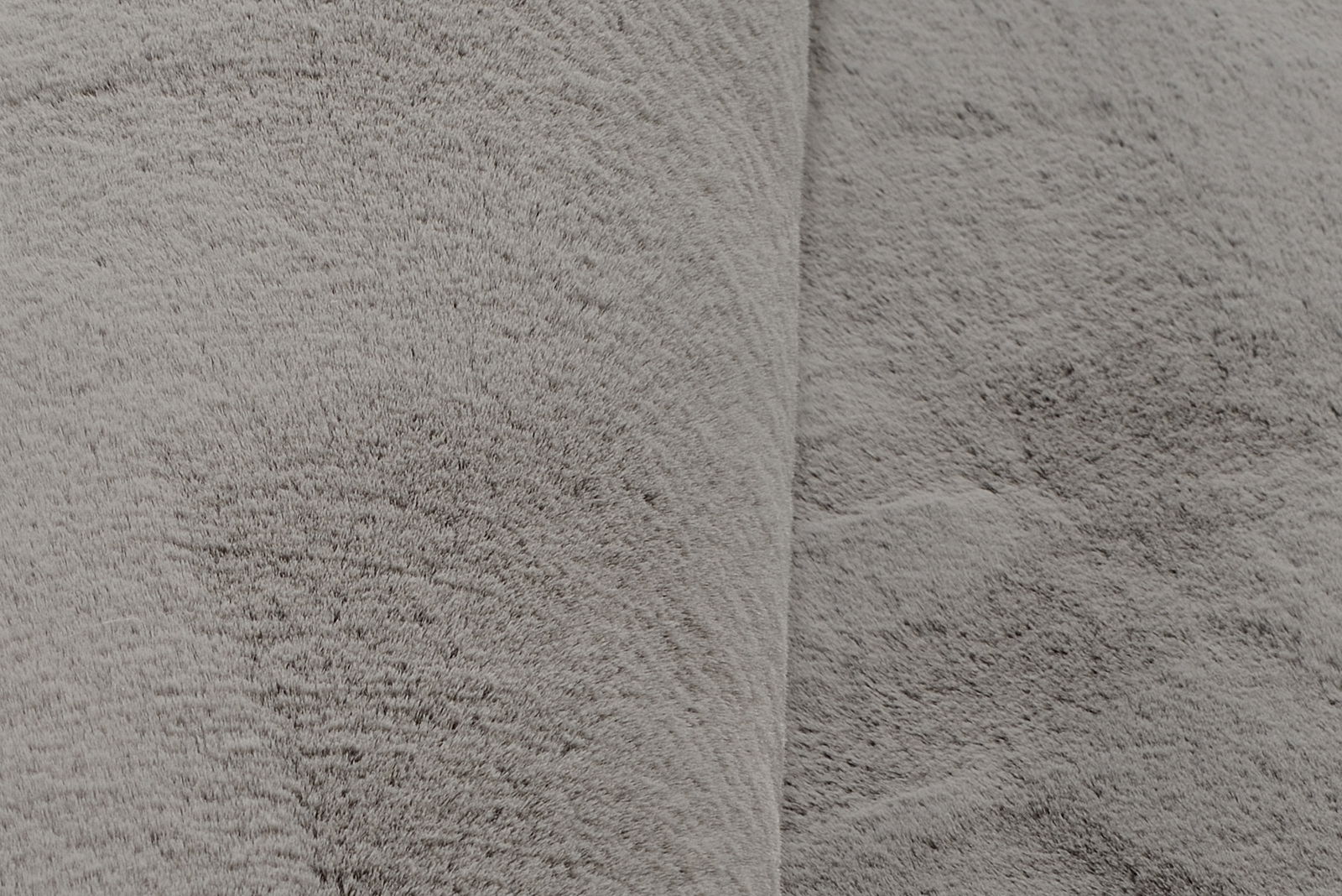 Nahaufnahme eines grauen Fellteppichs mit weicher Textur.