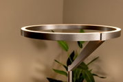 Moderne LED-Stehlampe mit ringförmigem Leuchtkopf in gebürstetem Metall, warmweiß leuchtender Lichtkante und schrägem Arm, seitliche Nahaufnahme auf den Lampenkopf