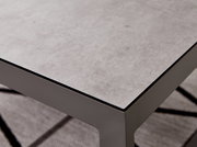 Nahaufnahme eines modernen Lounge-Tisches mit grauer Steinoptik-Oberfläche und stabilen Metallbeinen, perspektivisch von oben rechts fotografiert.
