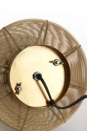 Unteransicht einer Tischleuchte mit einem goldenen, runden Metallgitter und einem schwarzen Kabel.