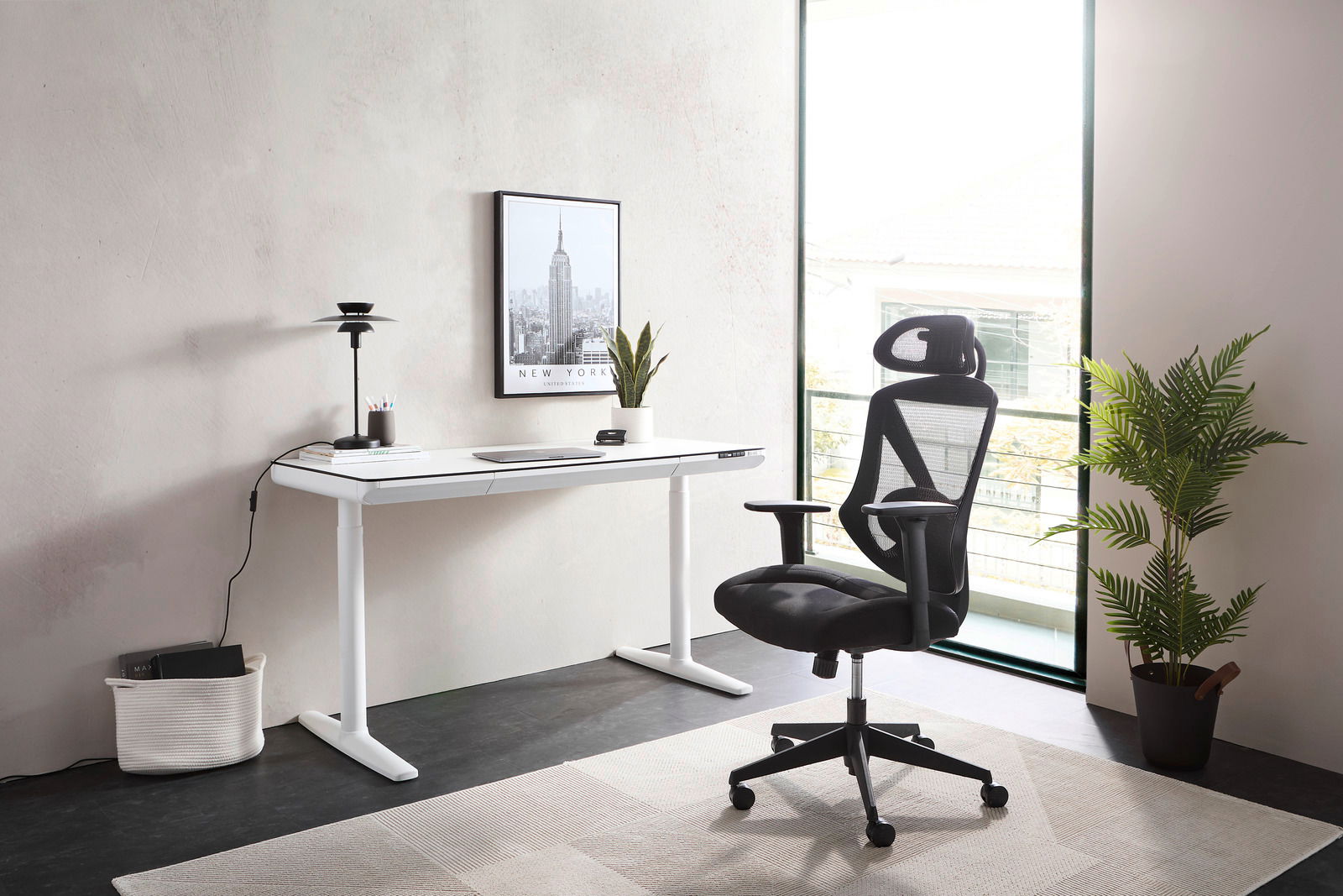 Moderner weißer E-Schreibtisch in einem hellen Raum, seitliche Perspektive, mit einem ergonomischen schwarzen Bürostuhl und Dekorationen wie einer Pflanze und einem Bild an der Wand.