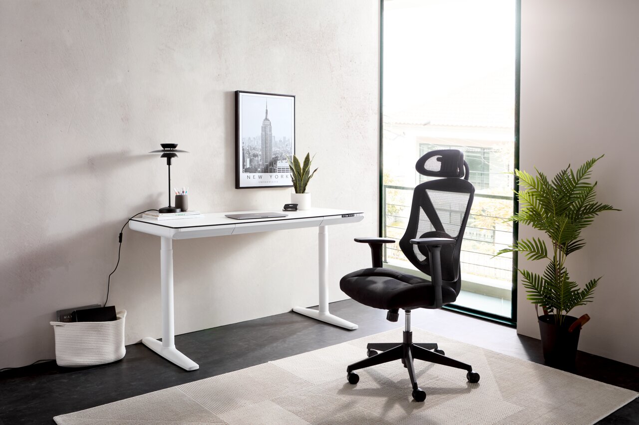 Modern wit elektrisch bureau in een lichte ruimte, gezien vanuit de zijkant, met een ergonomische zwarte bureaustoel en decoraties zoals een plant en een schilderij aan de muur.