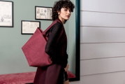 Vrouw met een wijnrode shopper over haar schouder, zijaanzicht