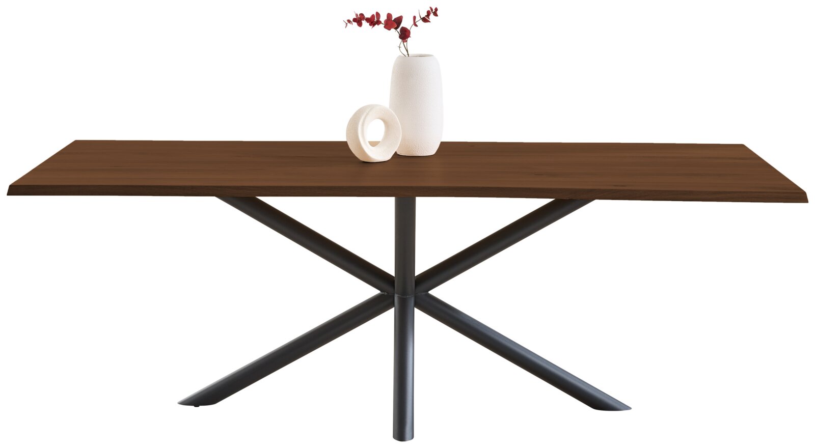 Rechthoekige eettafel met donkerbruin houten blad en zwart metalen kruispootonderstel, gefotografeerd van voren op ooghoogte tegen witte achtergrond, met witte vaas en rood blad als decoratie