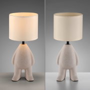 Moderne tafellamp met een witte stoffen kap en een sculpturale, beige gespikkelde keramische voet in de vorm van een figuur, vooraanzicht vanuit een licht verhoogd perspectief op een grijze achtergrond (links aan, rechts uit).