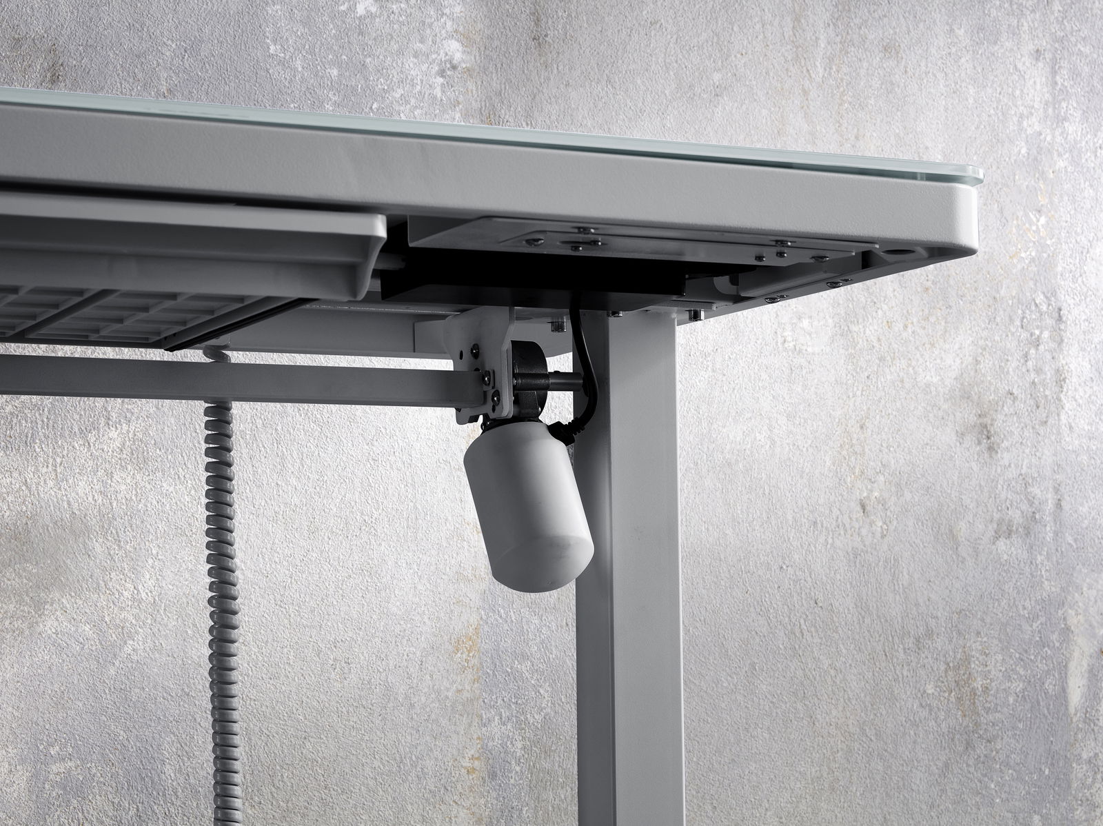 Nahaufnahme eines E-Schreibtischs von unten, die den Mechanismus und die Kabel zeigt.