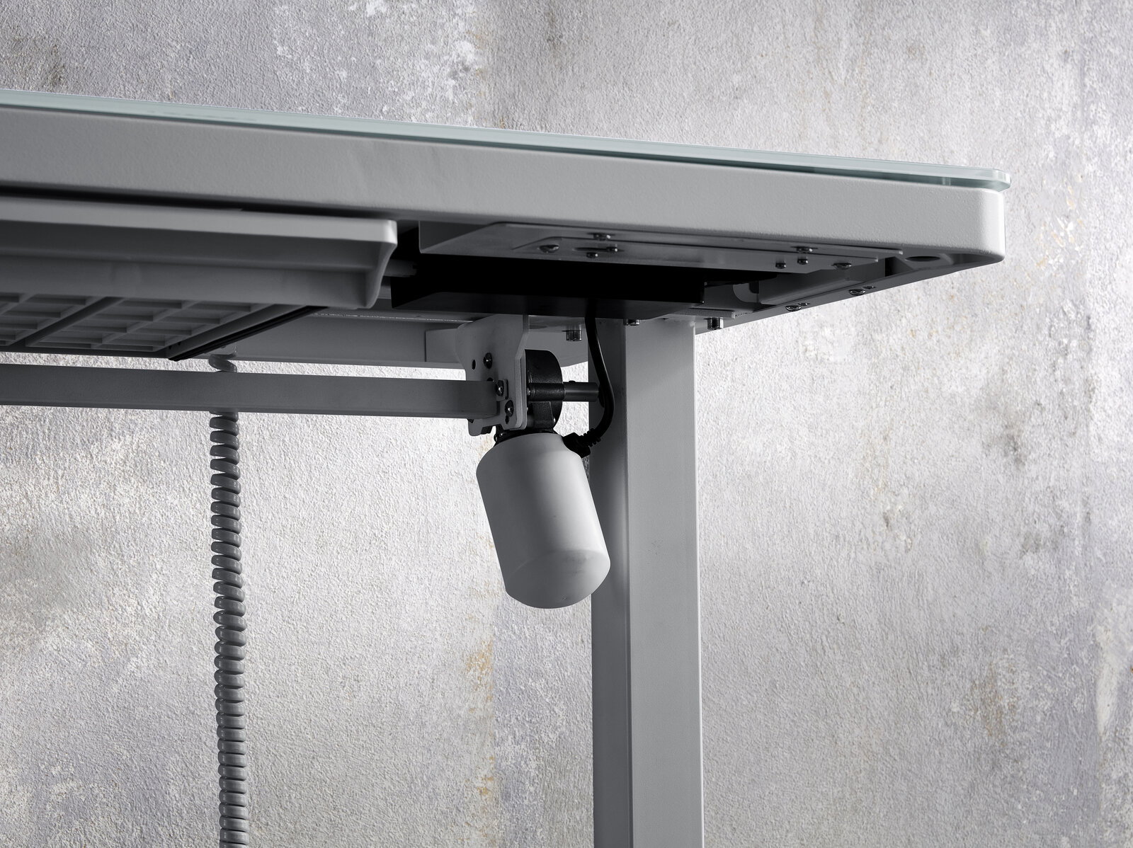 Nahaufnahme eines E-Schreibtischs von unten, die den Mechanismus und die Kabel zeigt.