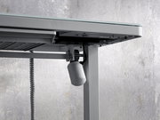 Nahaufnahme eines E-Schreibtischs von unten, die den Mechanismus und die Kabel zeigt.