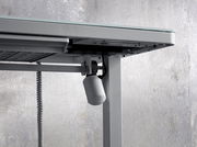 Nahaufnahme eines E-Schreibtischs von unten, die den Mechanismus und die Kabel zeigt.