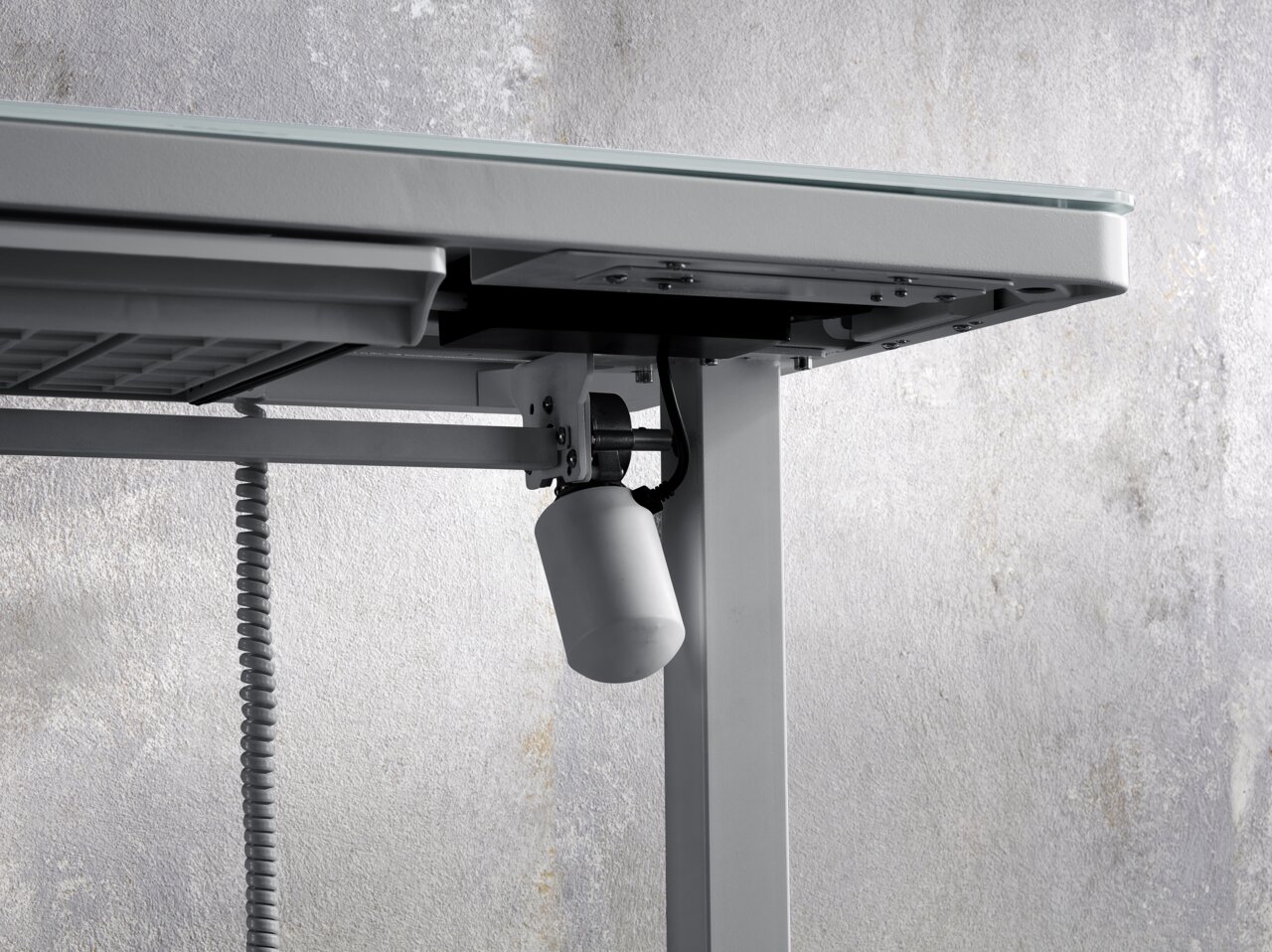 Nahaufnahme eines E-Schreibtischs von unten, die den Mechanismus und die Kabel zeigt.