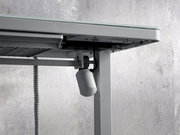 Nahaufnahme eines E-Schreibtischs von unten, die den Mechanismus und die Kabel zeigt.