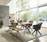 Moderner Esstisch 180x90 aus Holz mit Metallbeinen, umgeben von stilvollen Stühlen und einer Bank, in einem hellen Raum mit großen Fenstern, seitliche Perspektive.