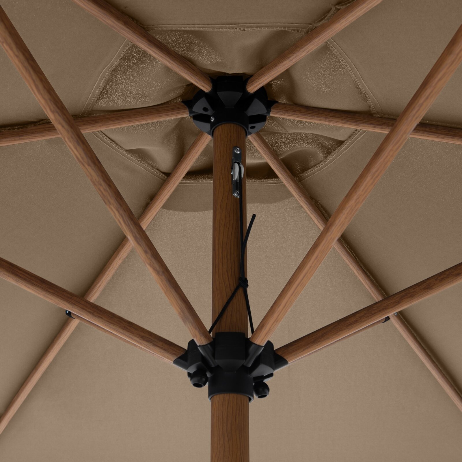 Unteransicht von unten: Detail der Innenseite eines beigen Sonnenschirms mit Holzoptik-Streben, schwarzer Nabe und Mittelstange mit Zugseil