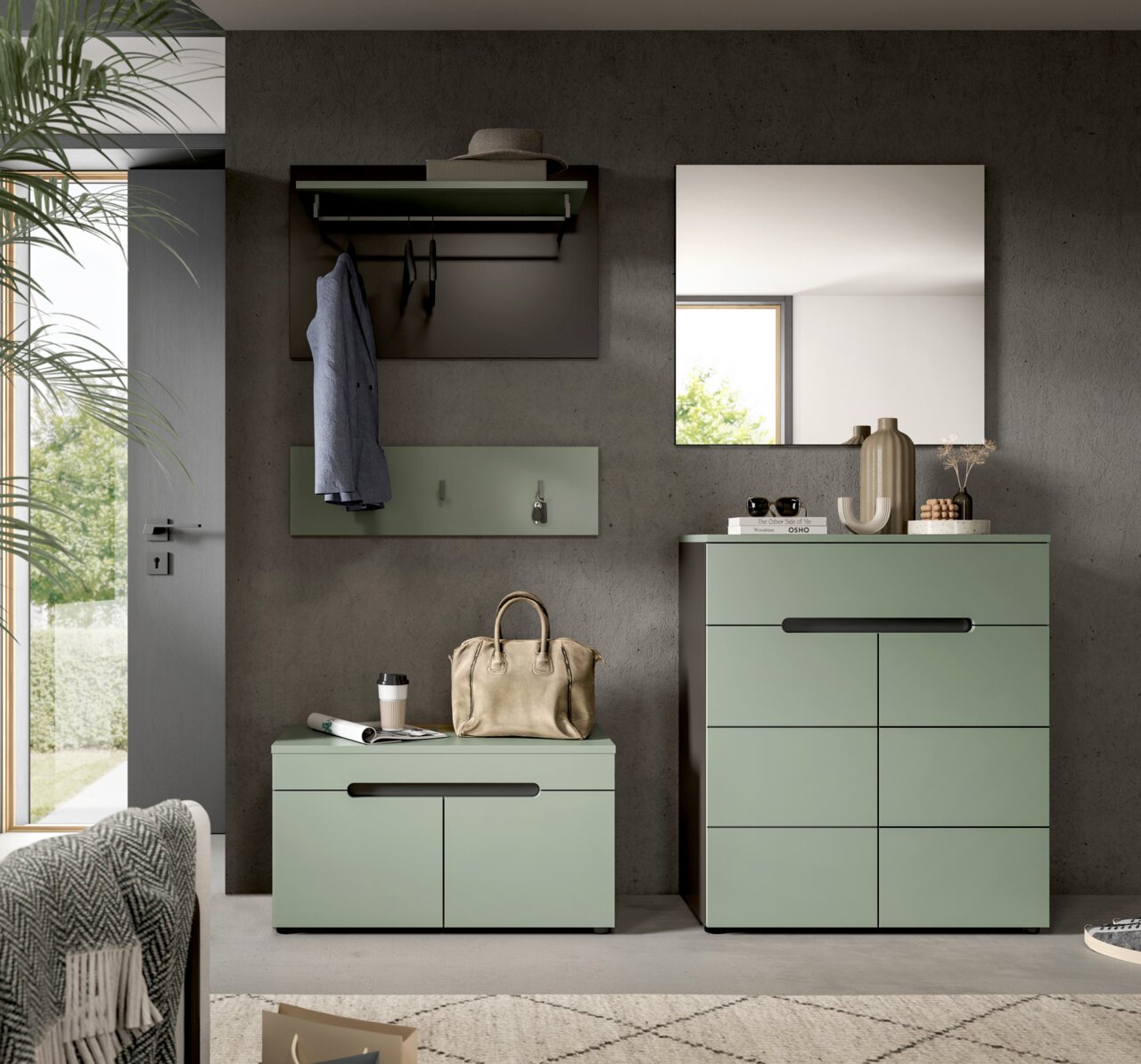 Modernes Flur-Set in Salbeigrün mit Kommode und Schuhbank, Wandgarderobe und Spiegel vor Betonwand, frontal aus Augenhöhe fotografiert.