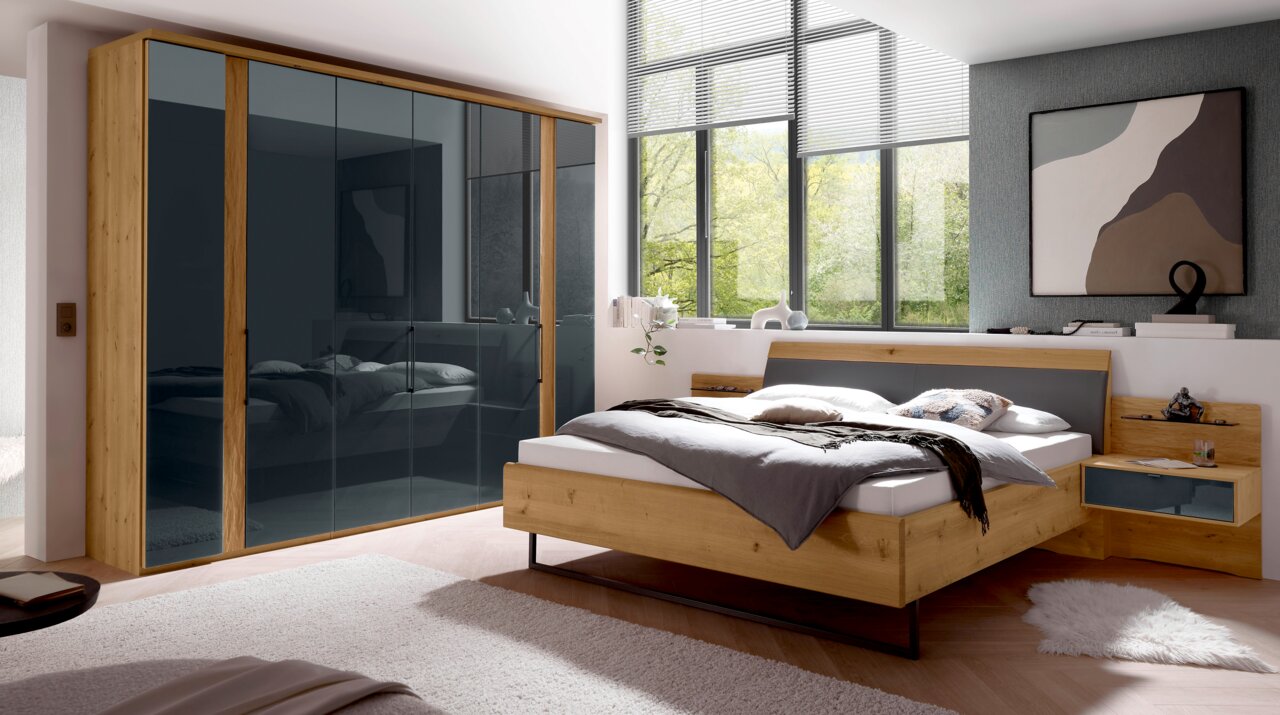 Moderner 6-türiger Drehtürenschrank in Holzoptik mit dunklen Glaselementen, seitliche Perspektive im stilvollen Schlafzimmer.