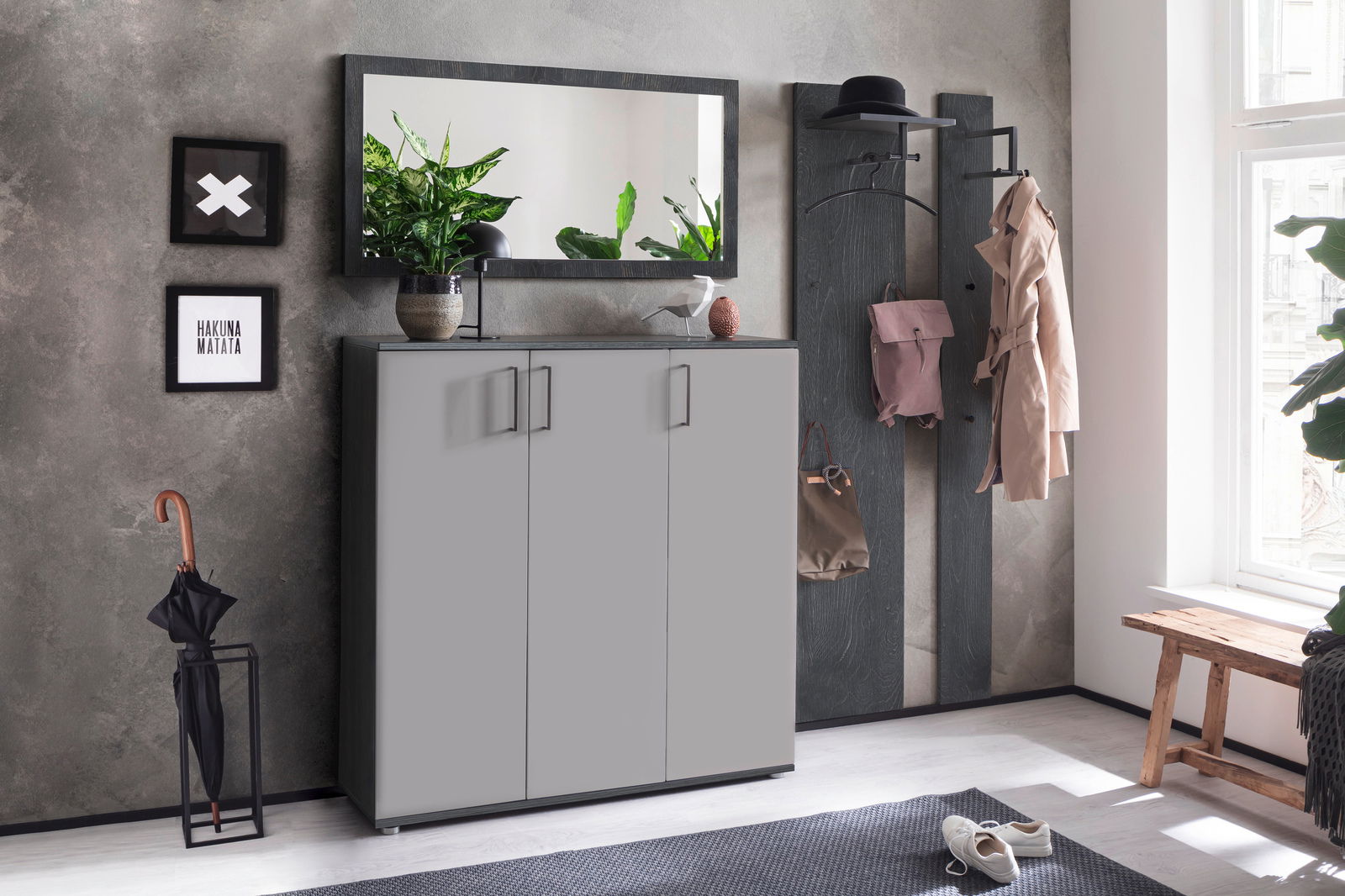 Moderne Garderobe mit grauem Schrank, Spiegel, Hakenleiste und Dekorationen in einem hellen Raum, seitliche Perspektive.