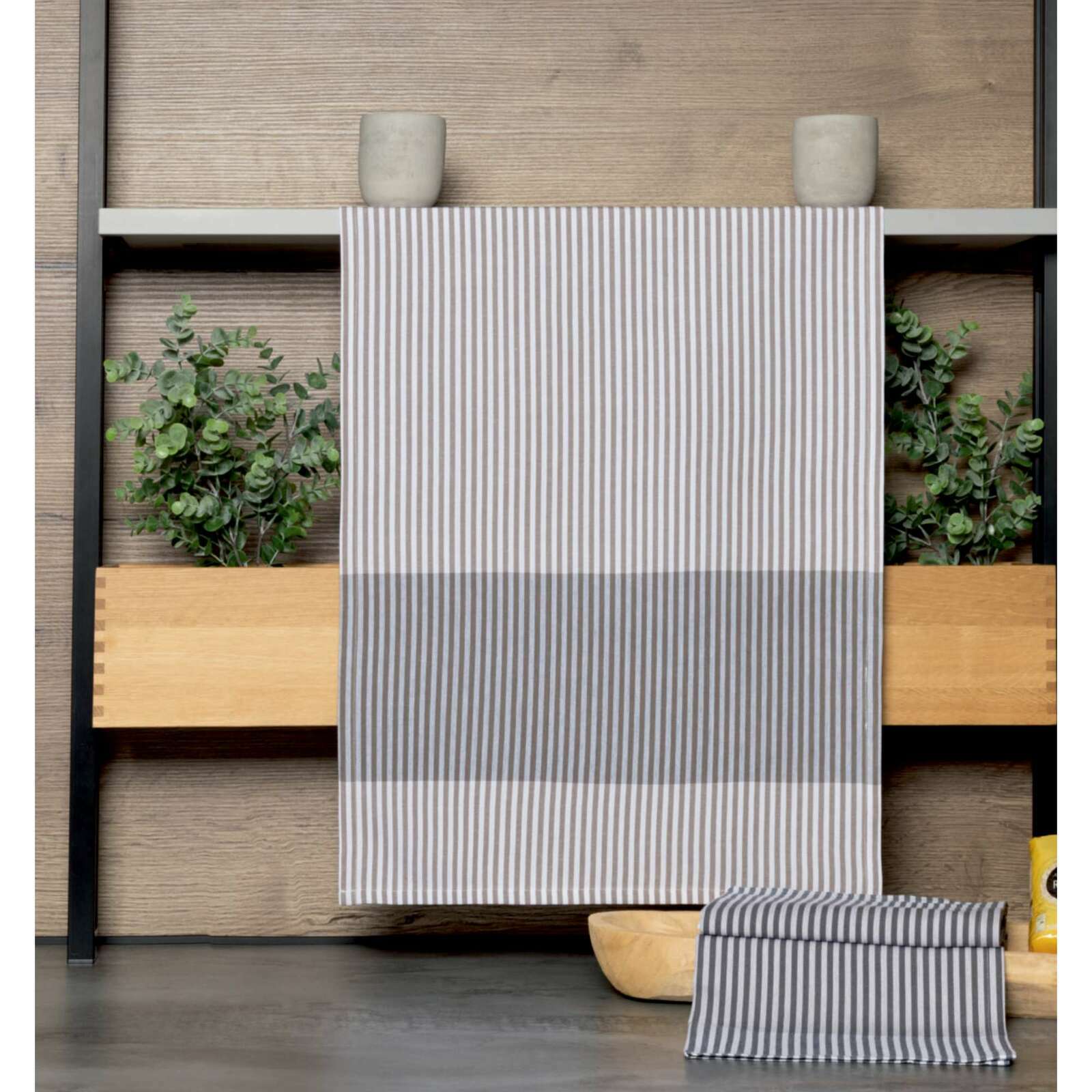 Gestreiftes Geschirrtuch in Grau und Weiß, hängend vor einem Holzregal mit Pflanzen, Vorderansicht