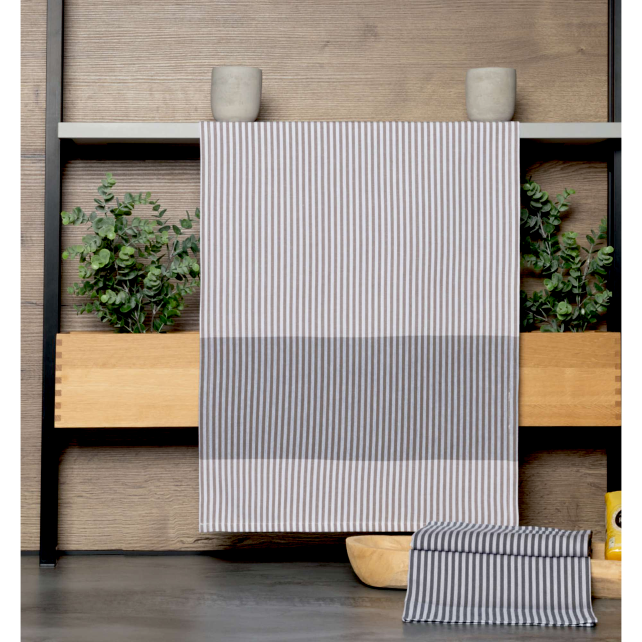Gestreiftes Geschirrtuch in Grau und Weiß, hängend vor einem Holzregal mit Pflanzen, Vorderansicht