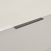Schwarzer, schlanker Griff an einer hellen Schrank- oder Schubladenfront, Detailaufnahme aus seitlicher Perspektive