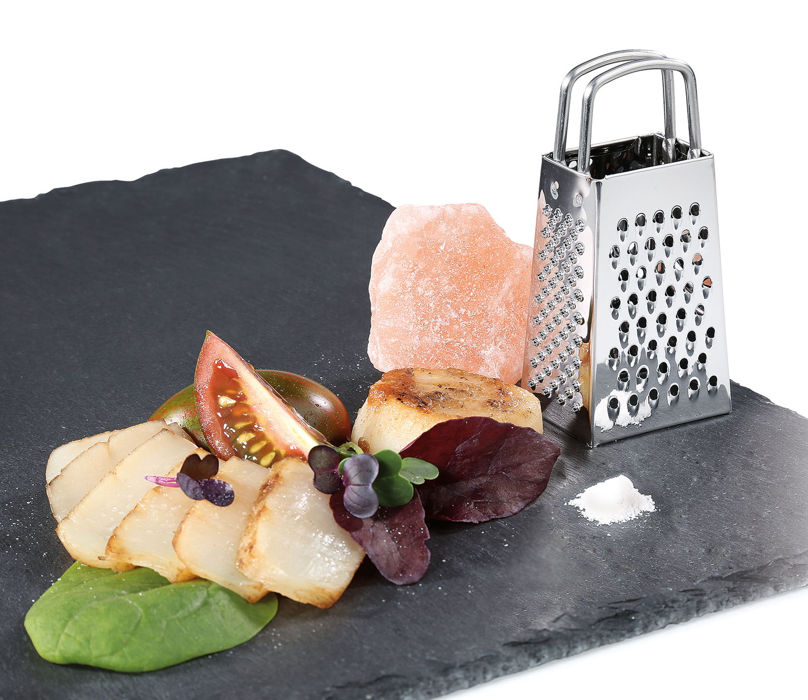 Mini-Vierkantreibe aus Edelstahl auf einer Schieferplatte, umgeben von frischen Zutaten, aus seitlicher Perspektive.