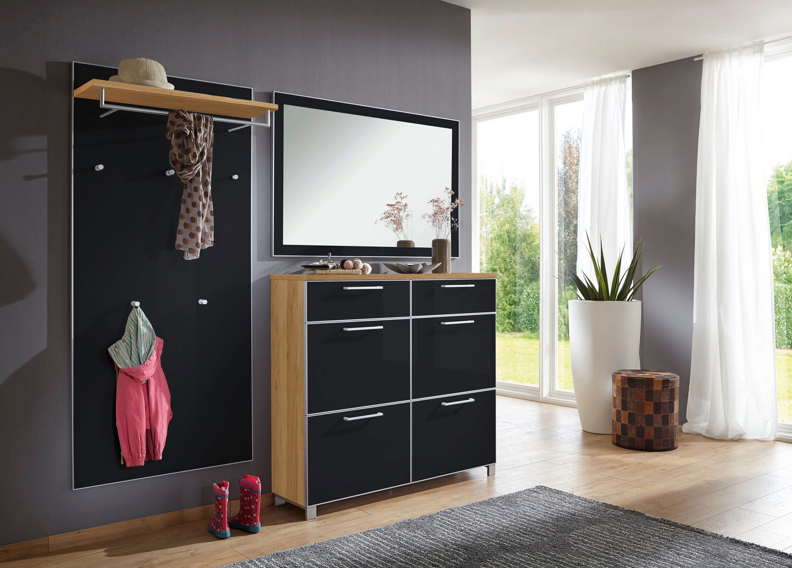 VOSS Garderoben-Set 3-tlg. SANTINA Modernes Garderoben-Set in einem hellen Raum mit großem Fenster, bestehend aus einer schwarzen Wandpaneele mit Haken, einem Spiegel und einem Schrank mit Holzrahmen und schwarzen Fronten. Perspektive von vorne.