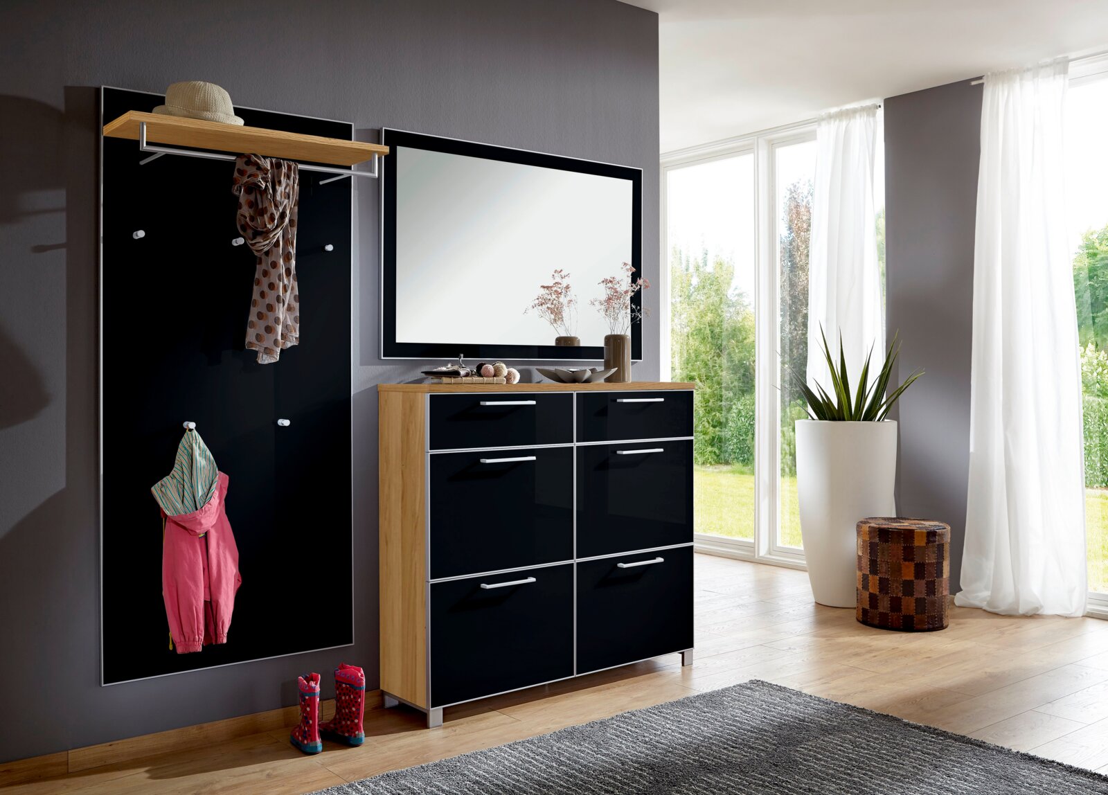 VOSS Garderoben-Set 3-tlg. SANTINA Modernes Garderoben-Set in einem hellen Raum mit großem Fenster, bestehend aus einer schwarzen Wandpaneele mit Haken, einem Spiegel und einem Schrank mit Holzrahmen und schwarzen Fronten. Perspektive von vorne.