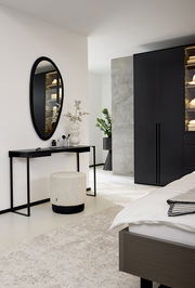 Moderner Konsolentisch in einem Schlafzimmer, seitliche Perspektive, mit schwarzem Metallrahmen und dekorativen Objekten darauf.