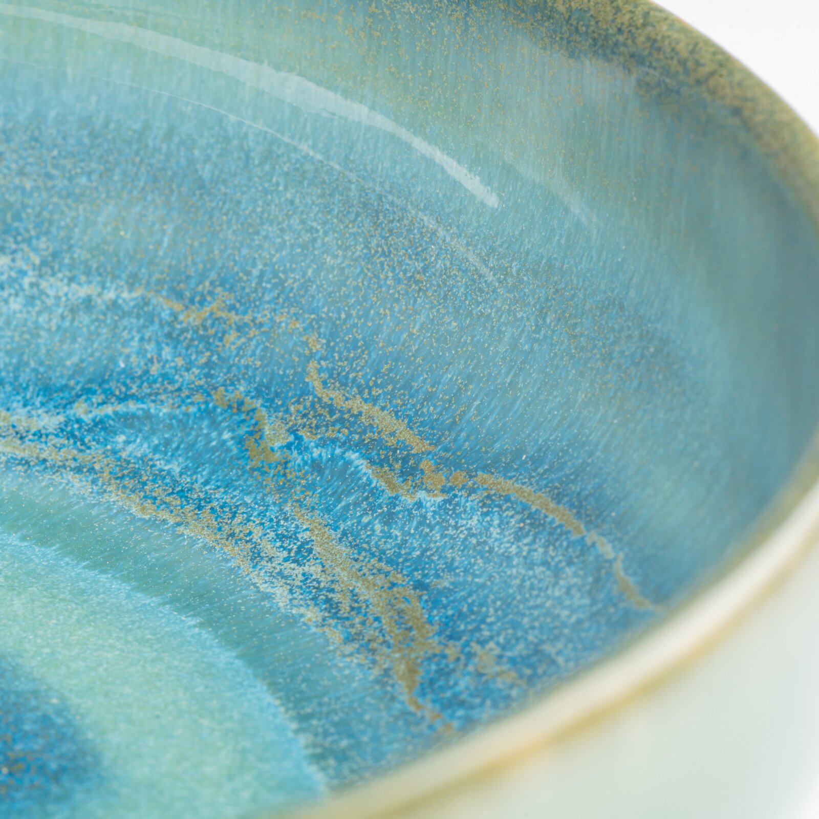 Makro-Nahaufnahme aus schräger Draufsicht auf eine runde, blau-türkis marmorierte Oberfläche mit goldenen Sprenkeln und glänzendem Finish