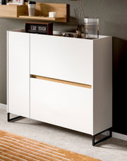 Modernes weißes Sideboard/Kommode mit schwarzem Metallgestell und Holz-Akzent, in einem Wohnraum dekoriert; Ansicht schräg von vorne rechts (3/4-Perspektive).