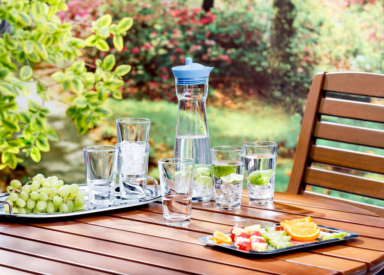 Leonardo Trinkglas EVENT Trinkglas Event 330ml auf einem Tisch im Freien, umgeben von weiteren Gläsern, einer Karaffe und Obst, aus der Vogelperspektive fotografiert.