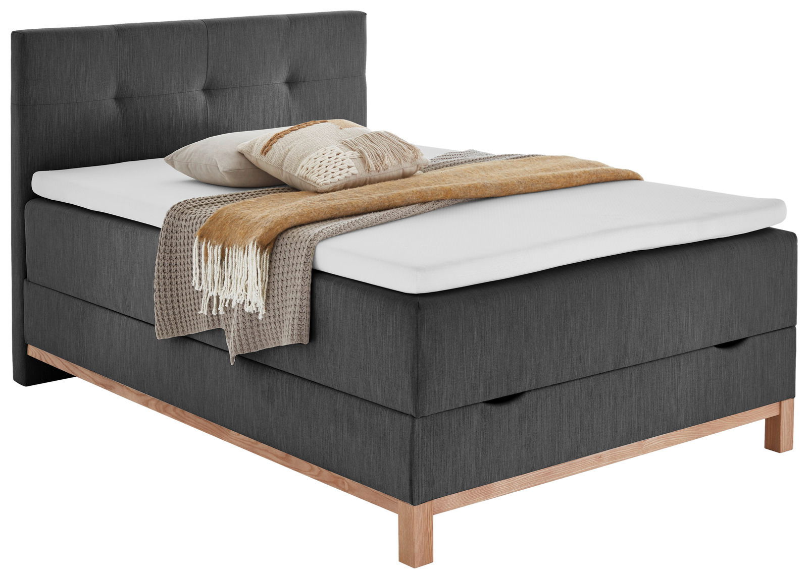 Graues Boxspringbett mit Holzfüßen, dekoriert mit Kissen und Decken, seitliche Perspektive