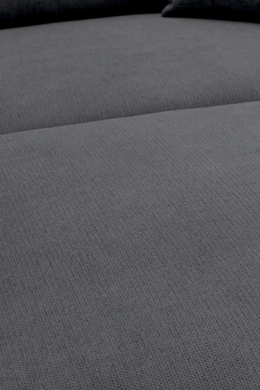 Nahaufnahme der grauen, strukturierten Polsteroberfläche eines Sofas, aufgenommen aus schräger Draufsicht.
